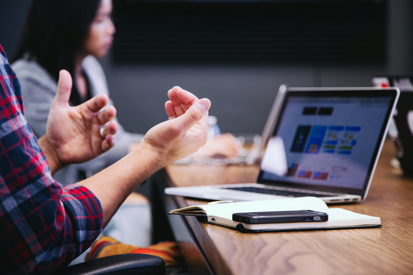 Hands gesturing in a meeting beside a laptop
