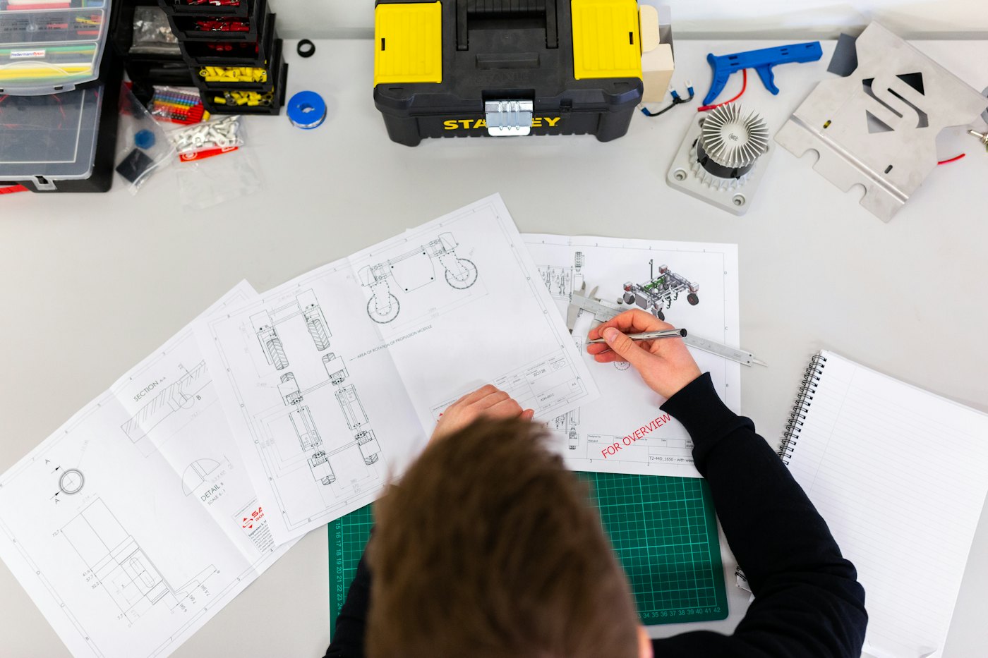 Overhead view of a person marking up technical drawings