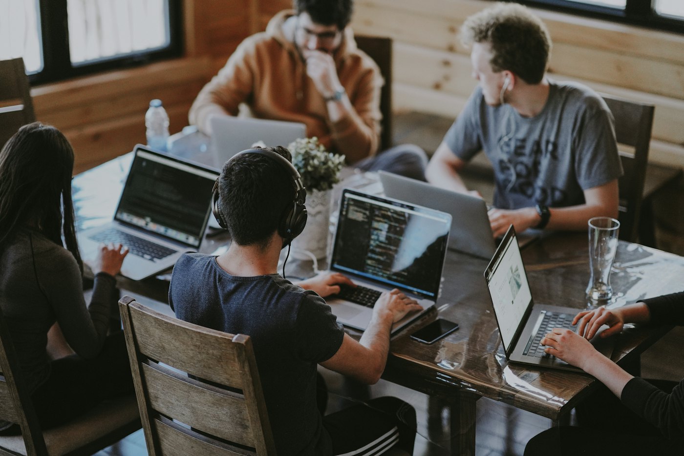 A small team working on laptops round a wooden table