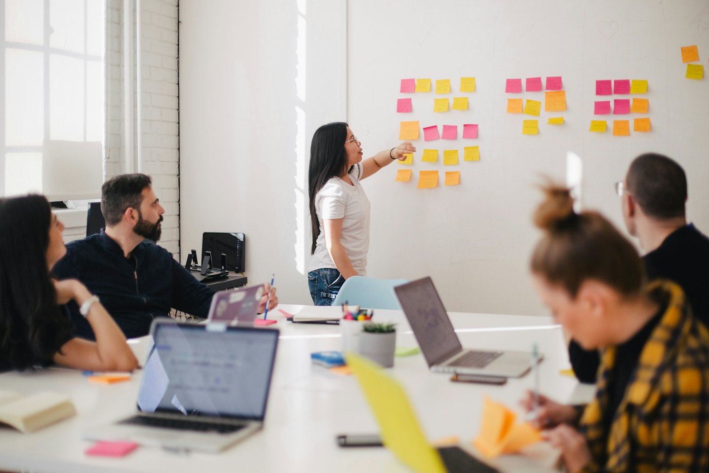 A facilitator leading a workshop with sticky notes on a whiteboard